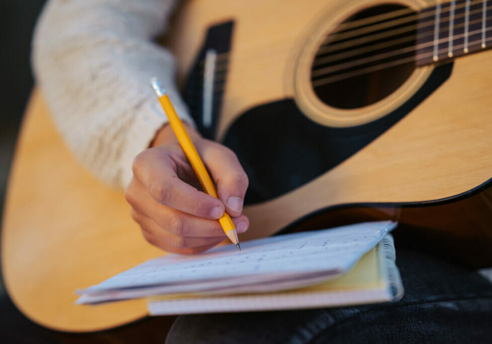 Close up of a girl musician composing song, writing down chords to the notes